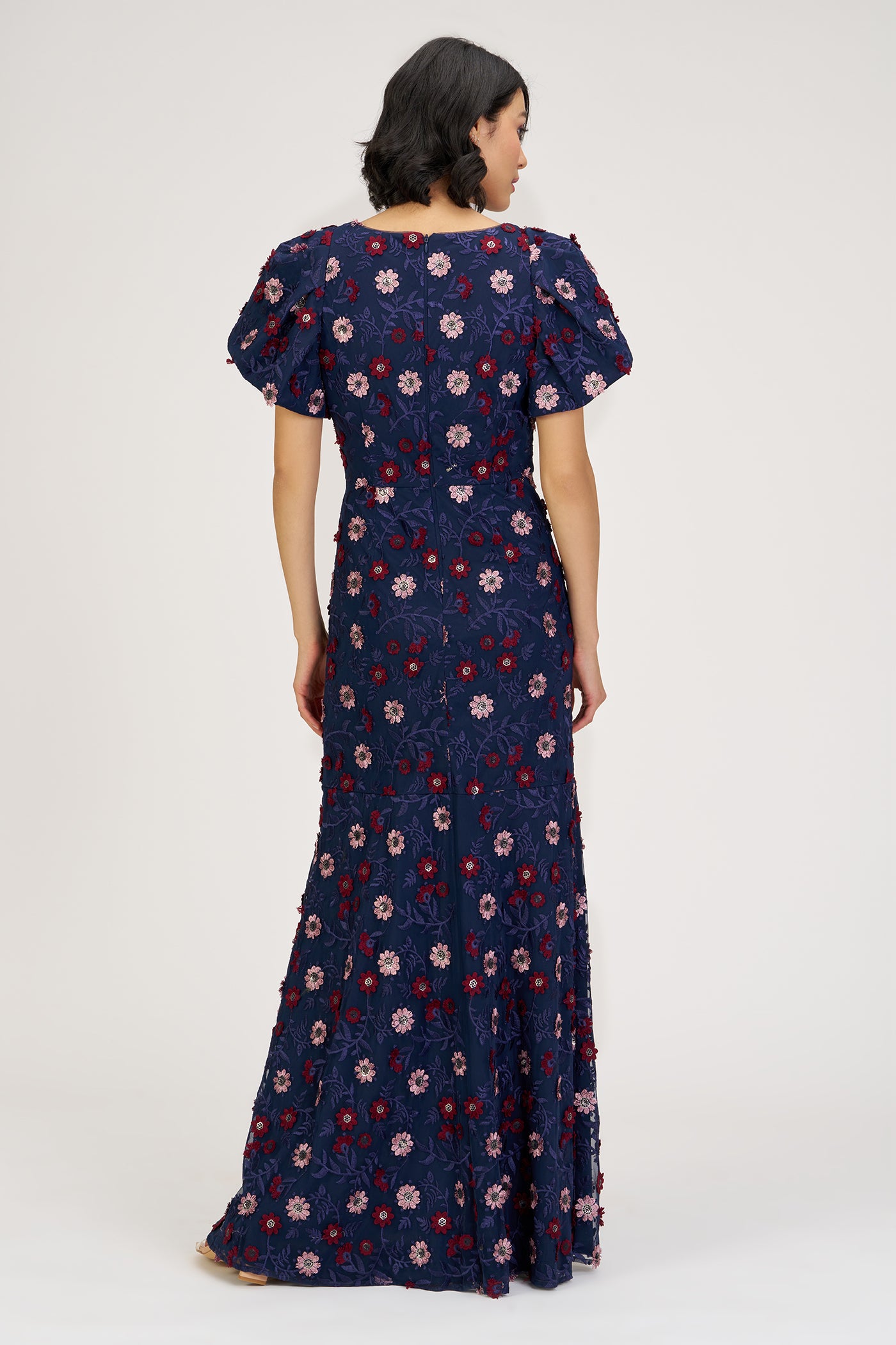 Woman wearing a navy floral dress on a white background