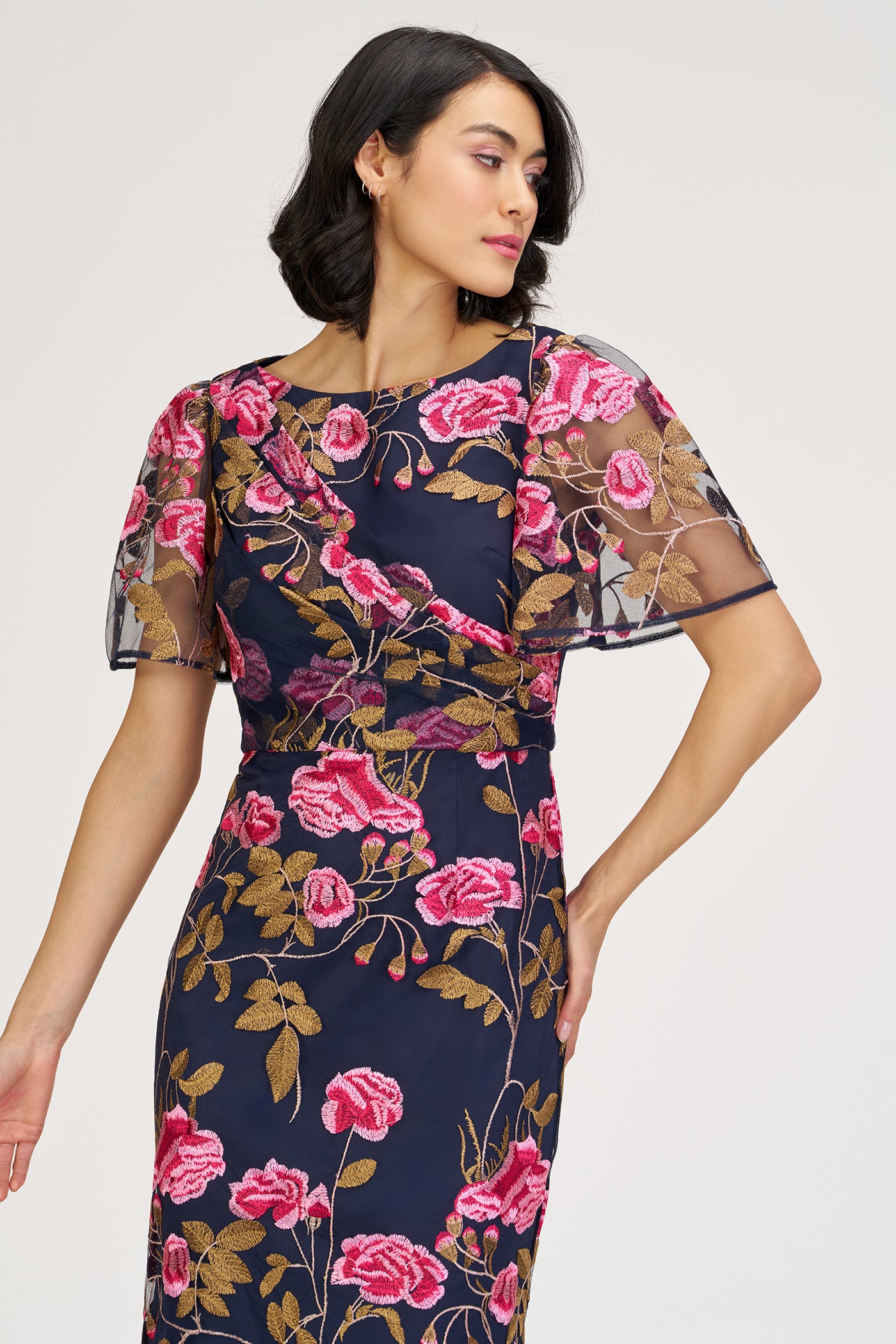 Woman wearing a navy dress with pink floral pattern on a white background