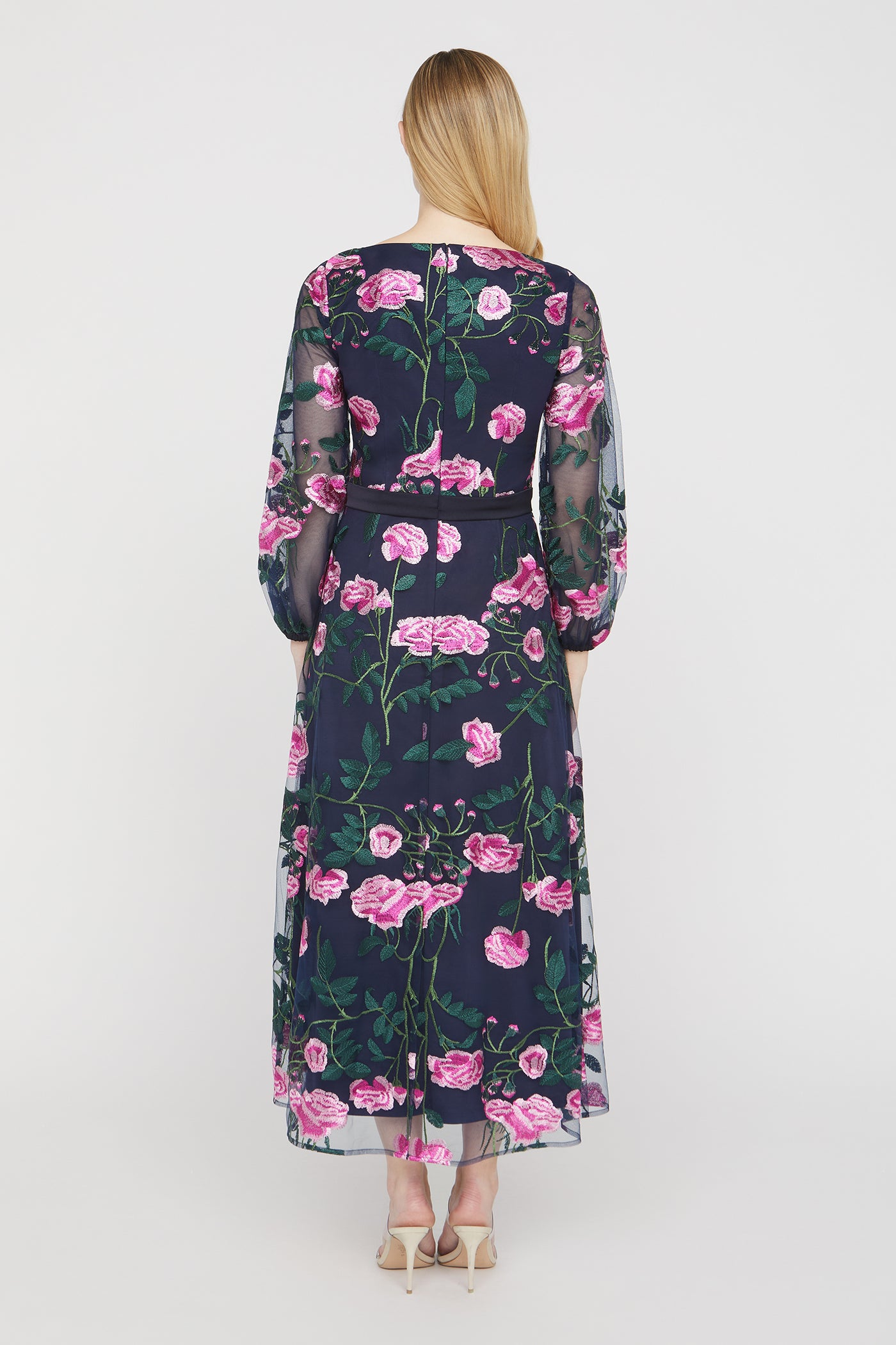 Woman wearing a floral dress with pink flowers on a white background