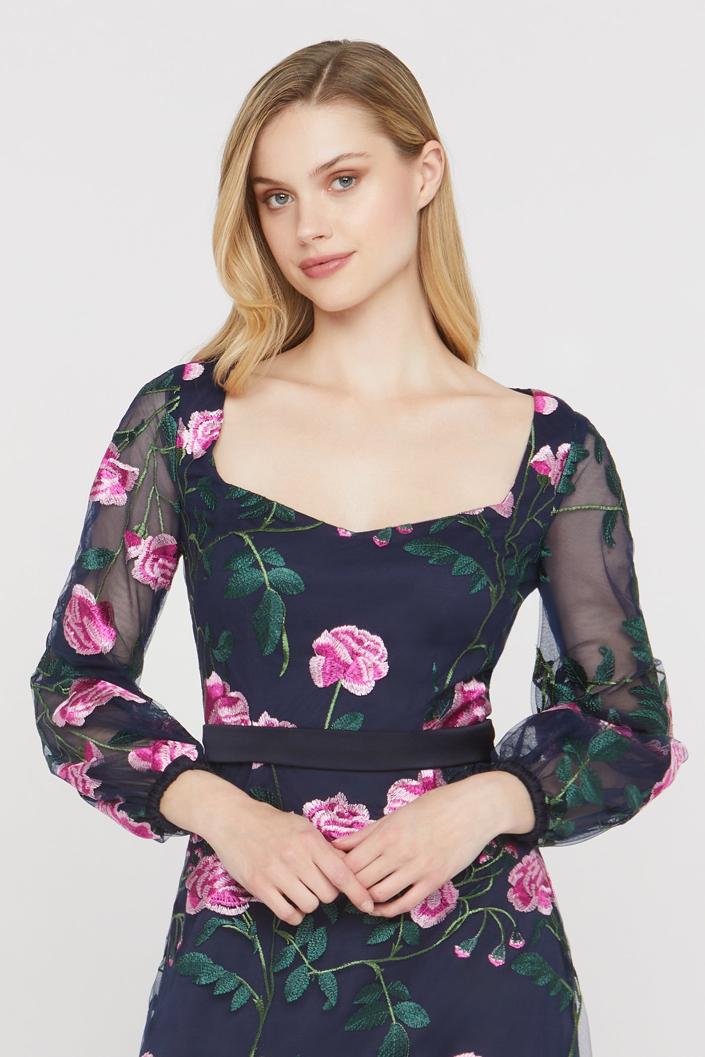 Woman wearing a floral dress with pink flowers and green leaves on a white background