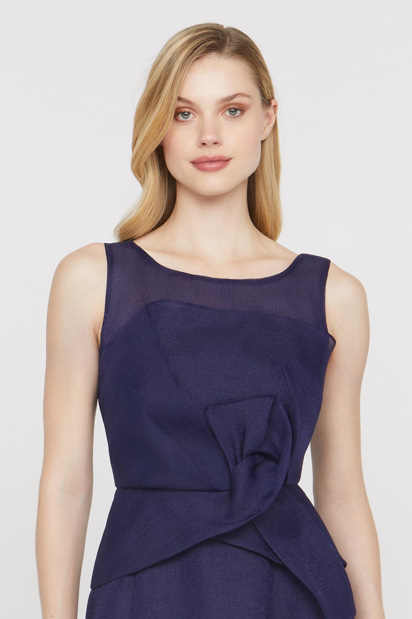 Woman wearing a dark purple dress with a draped design on a light gray background