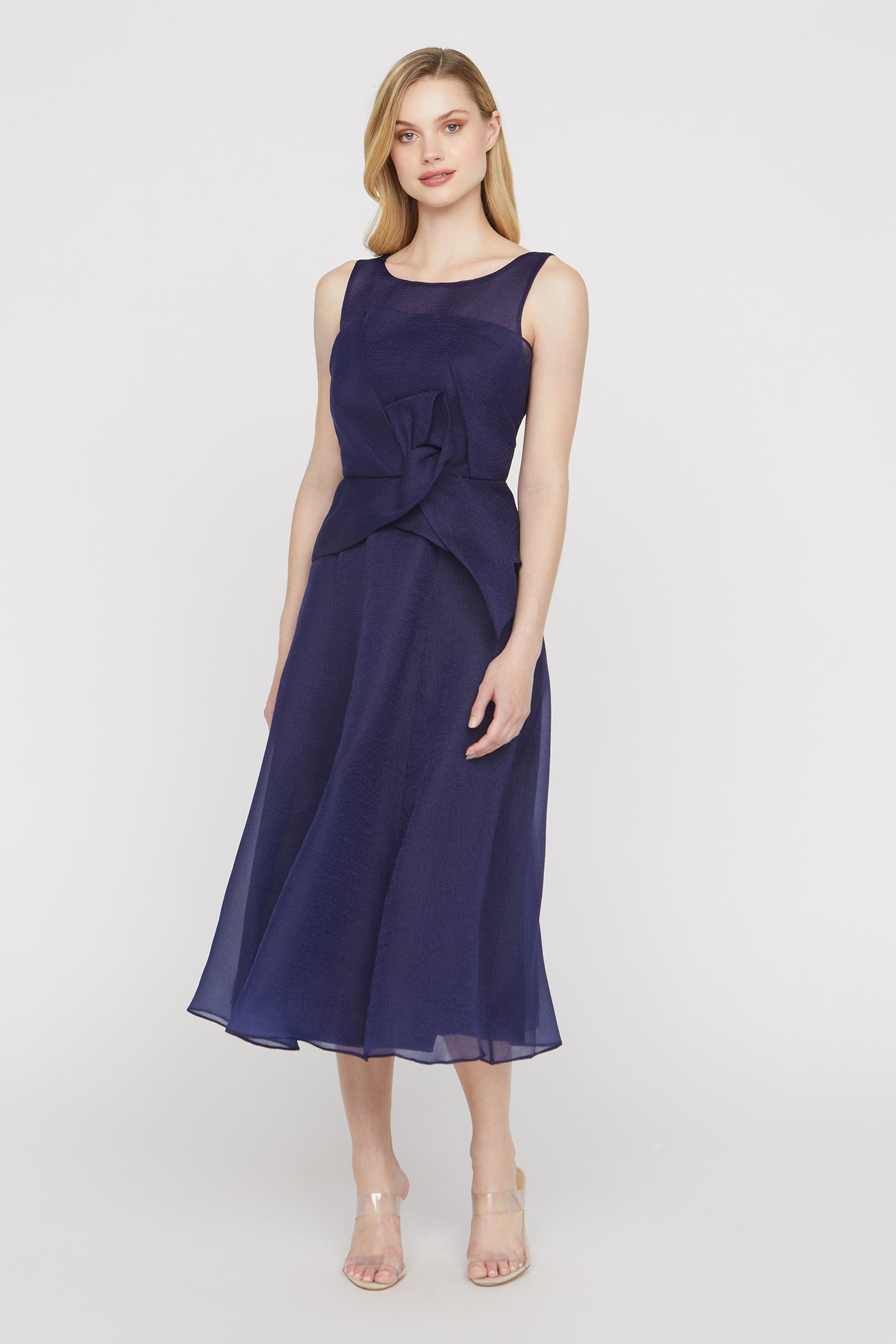 Woman wearing a navy blue dress with a bow detail on a white background