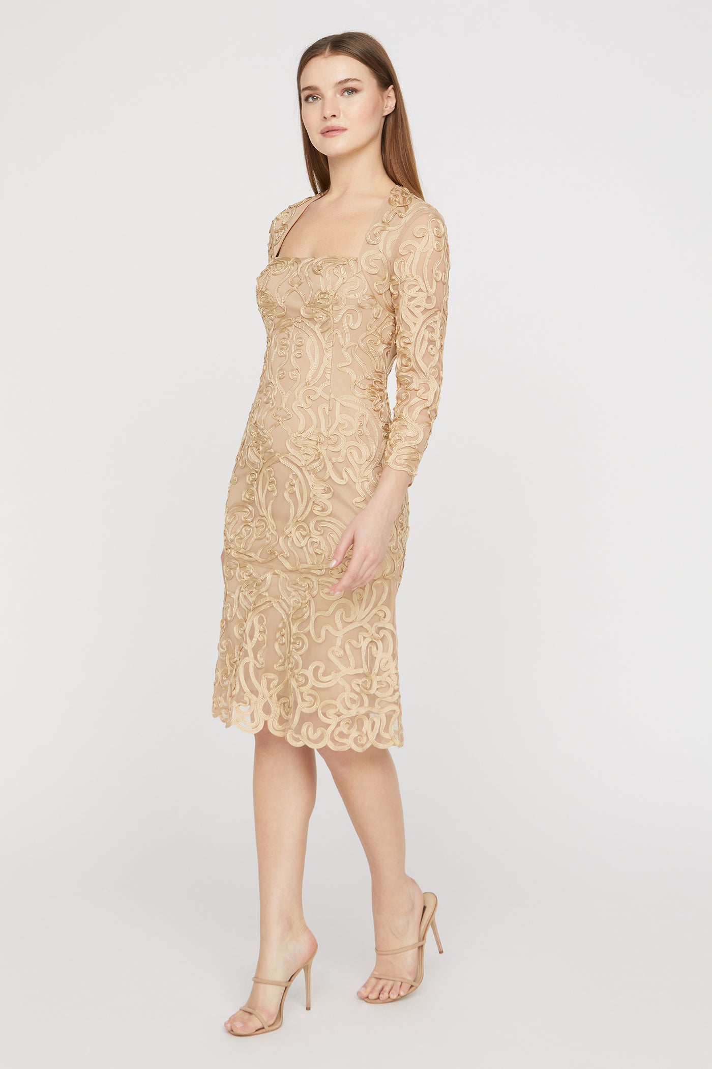Woman wearing a gold lace dress on a white background
