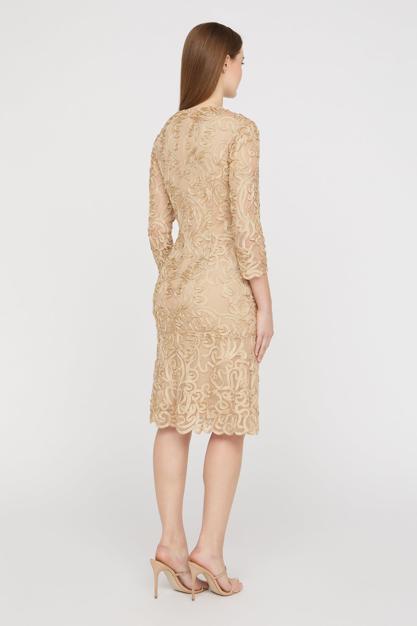 Woman wearing a beige lace dress on a white background