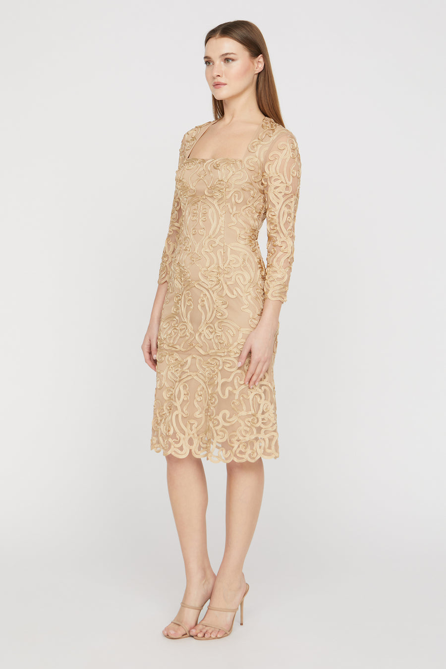 Woman wearing a beige lace dress on a white background