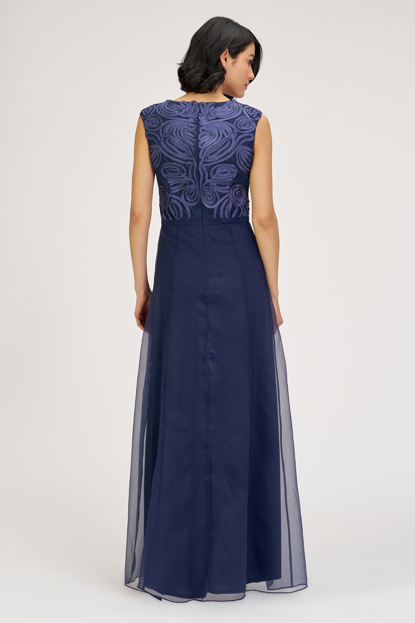 Navy blue evening gown with intricate top design on a white background
