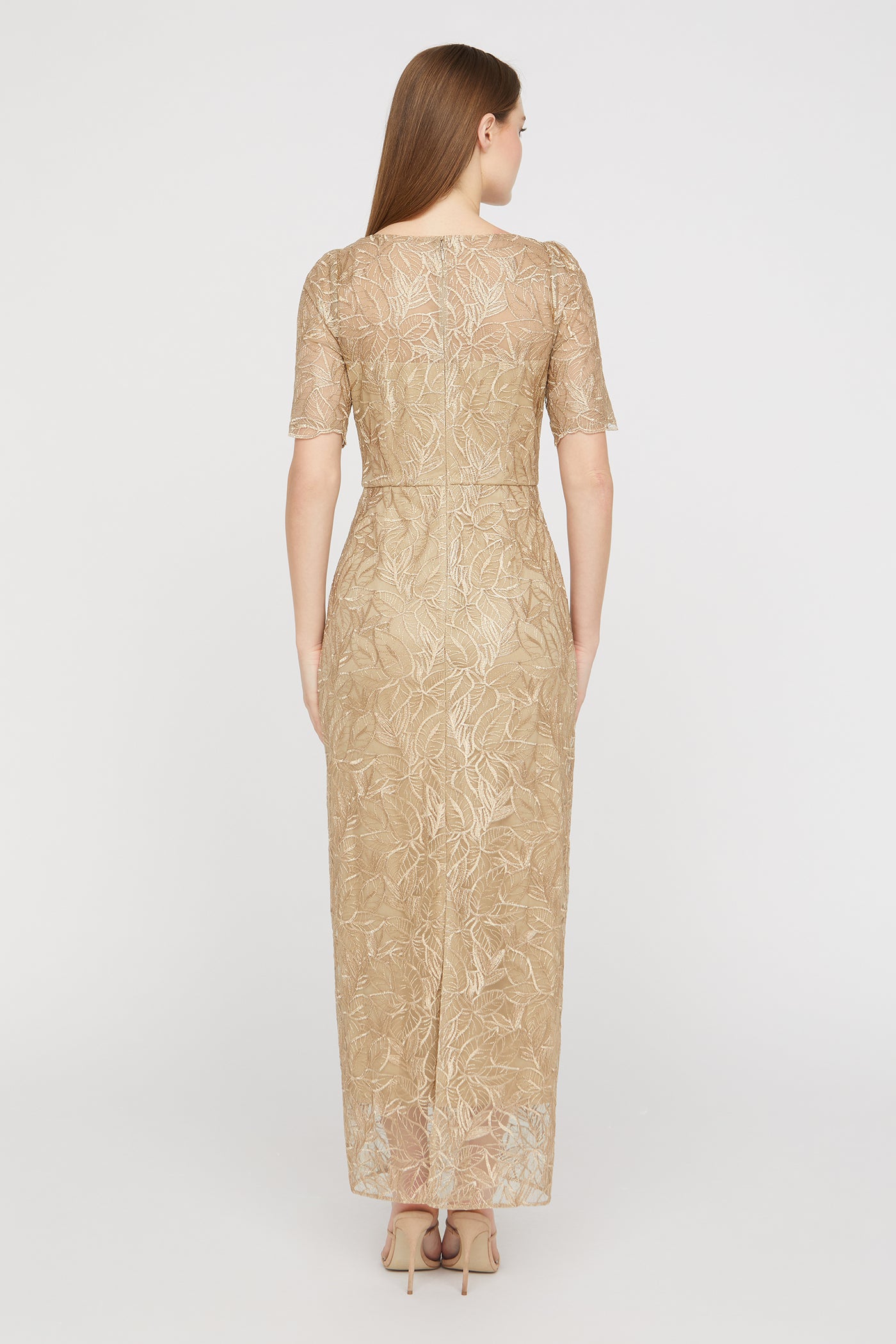 Woman wearing a gold lace dress on a white background