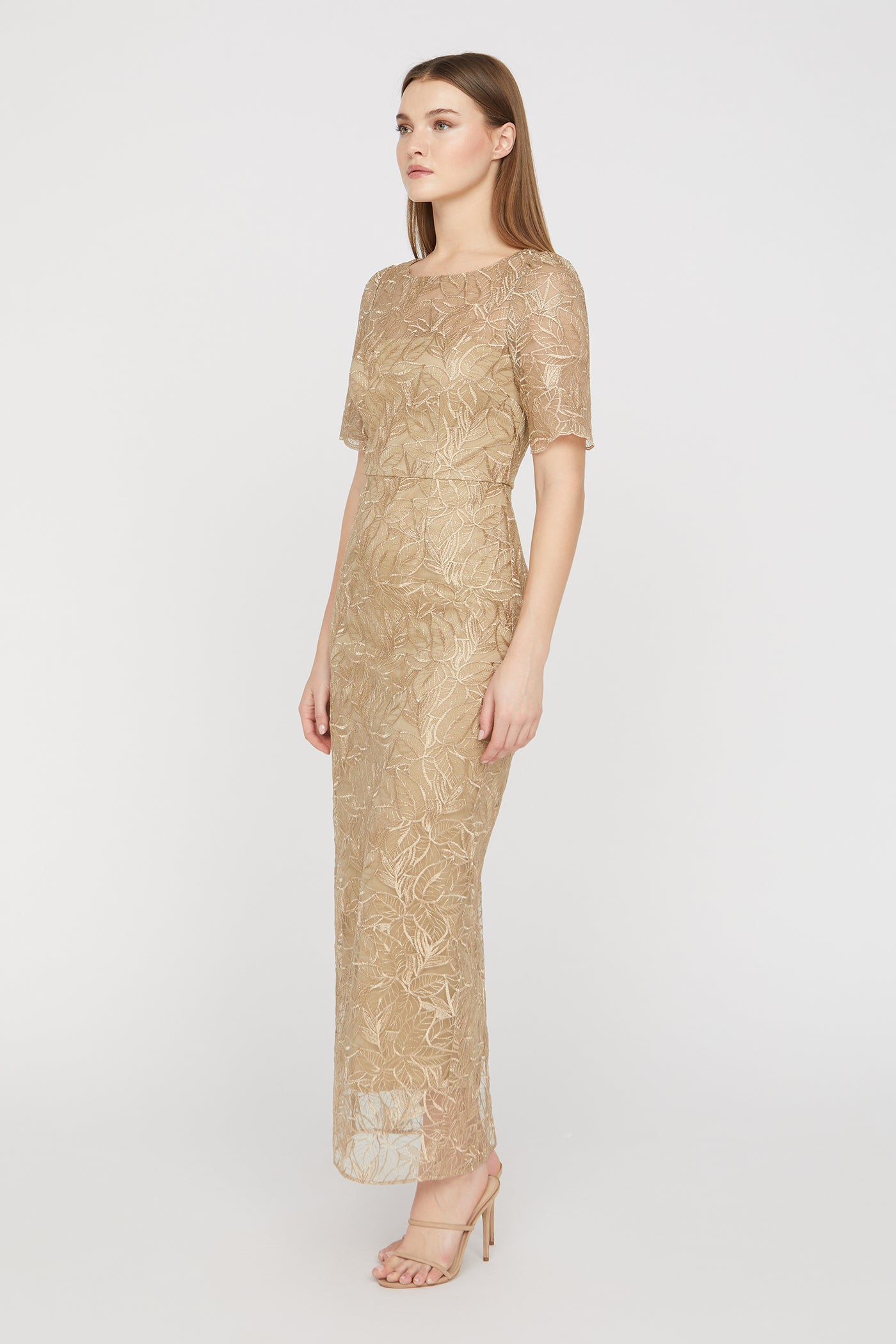Woman wearing a gold lace dress on a white background