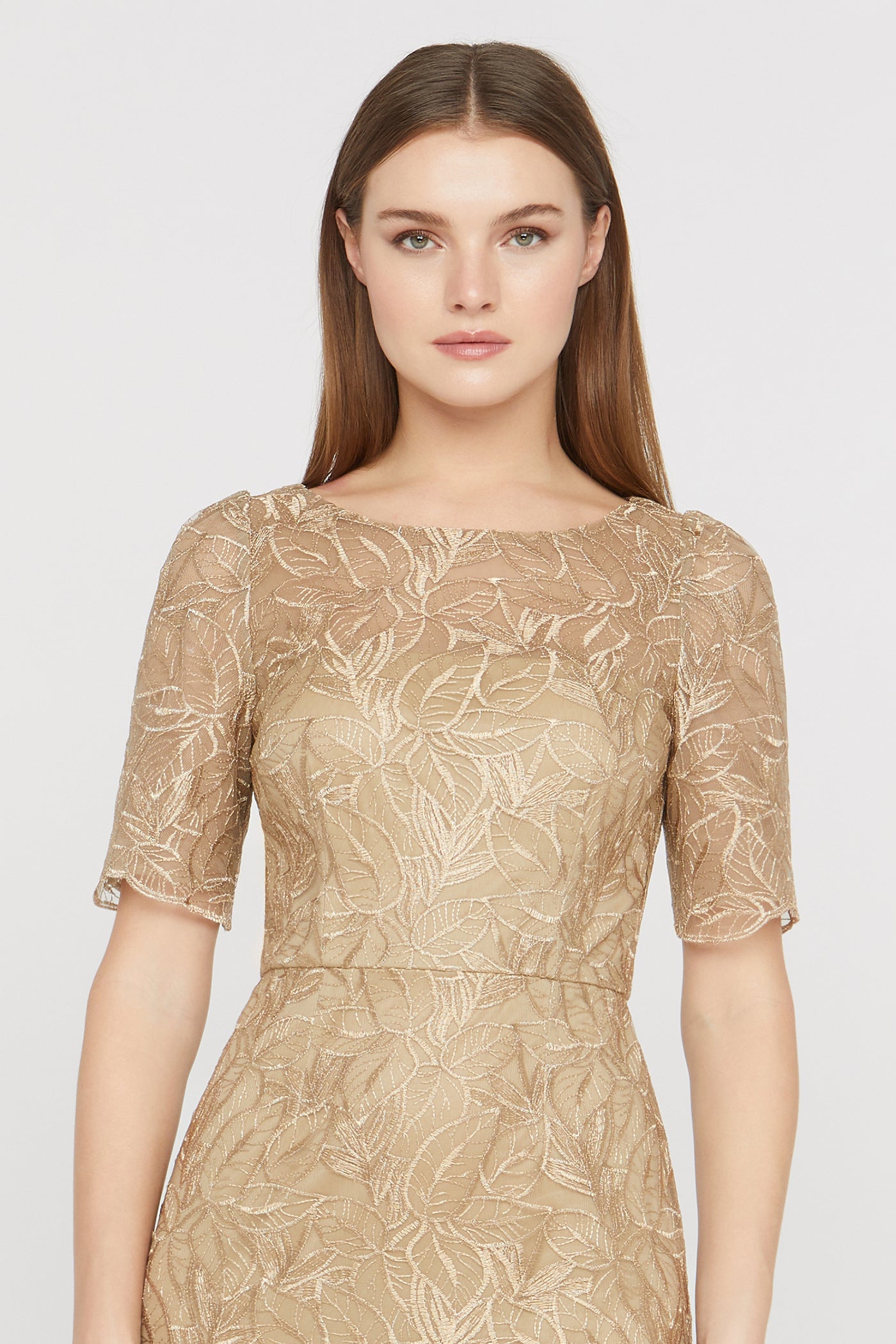Woman wearing a gold lace dress on a white background