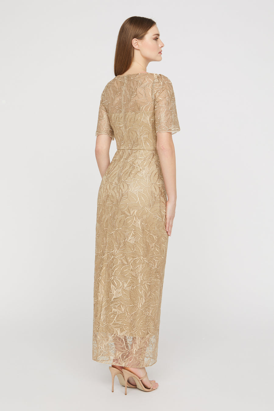 Woman wearing a gold lace dress on a white background