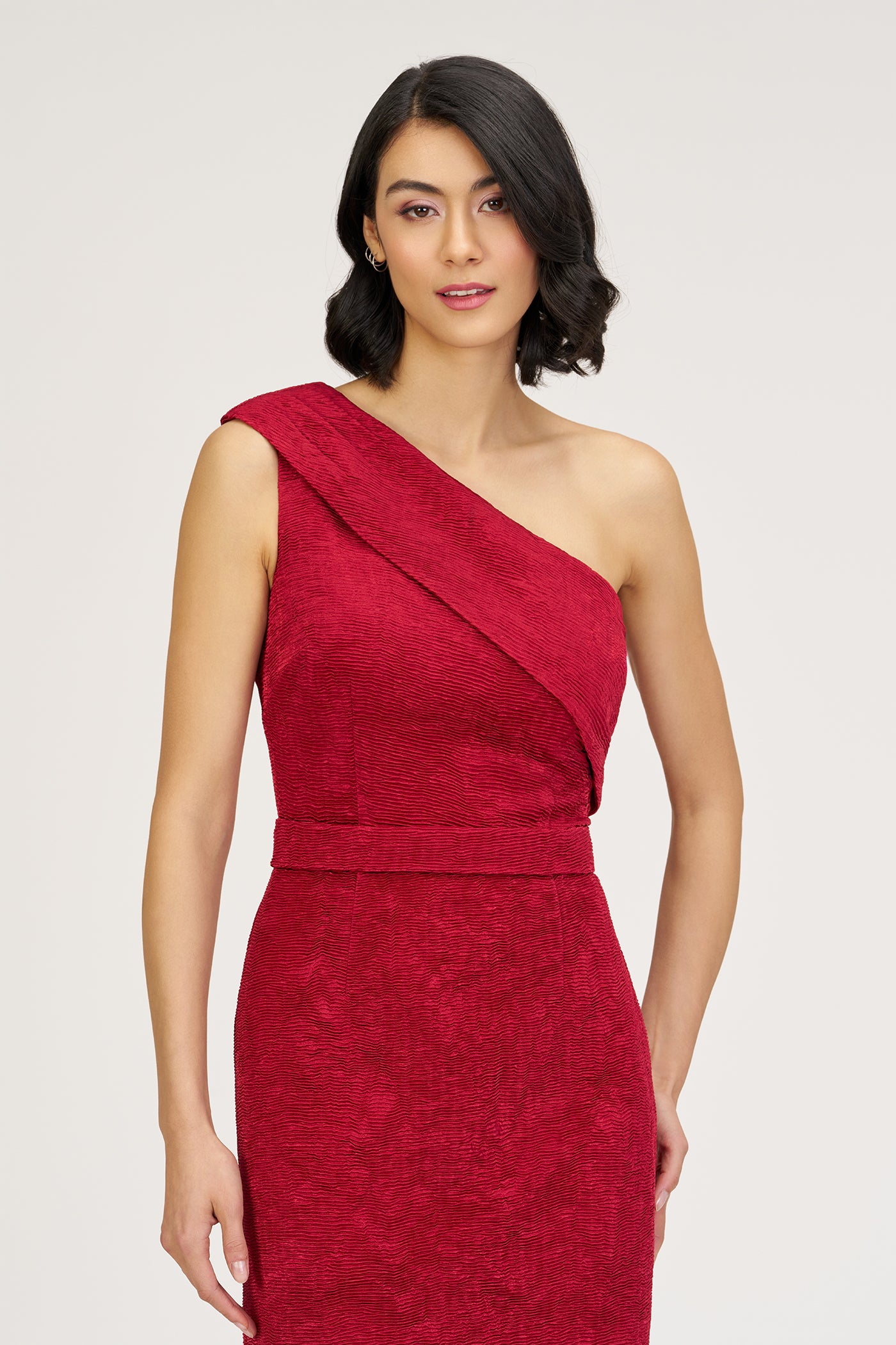 Woman wearing a red one-shoulder dress on a white background