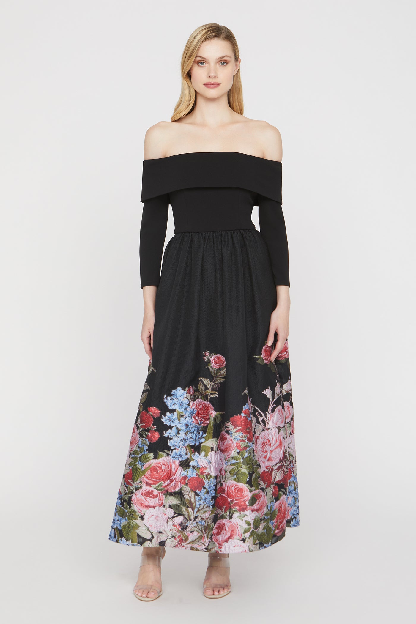Woman wearing a black off-shoulder dress with a floral skirt on a white background