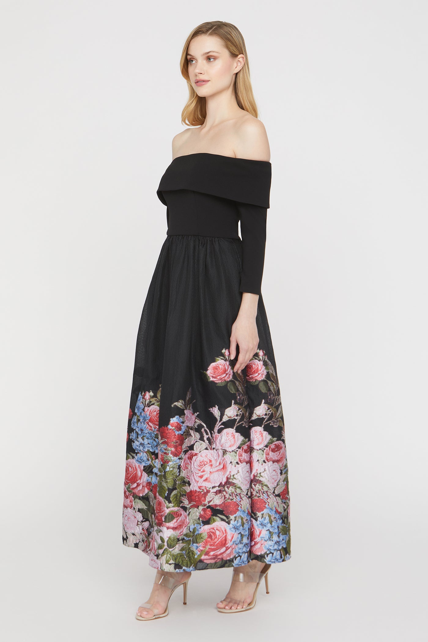 Woman wearing a black off-shoulder dress with floral print on a white background