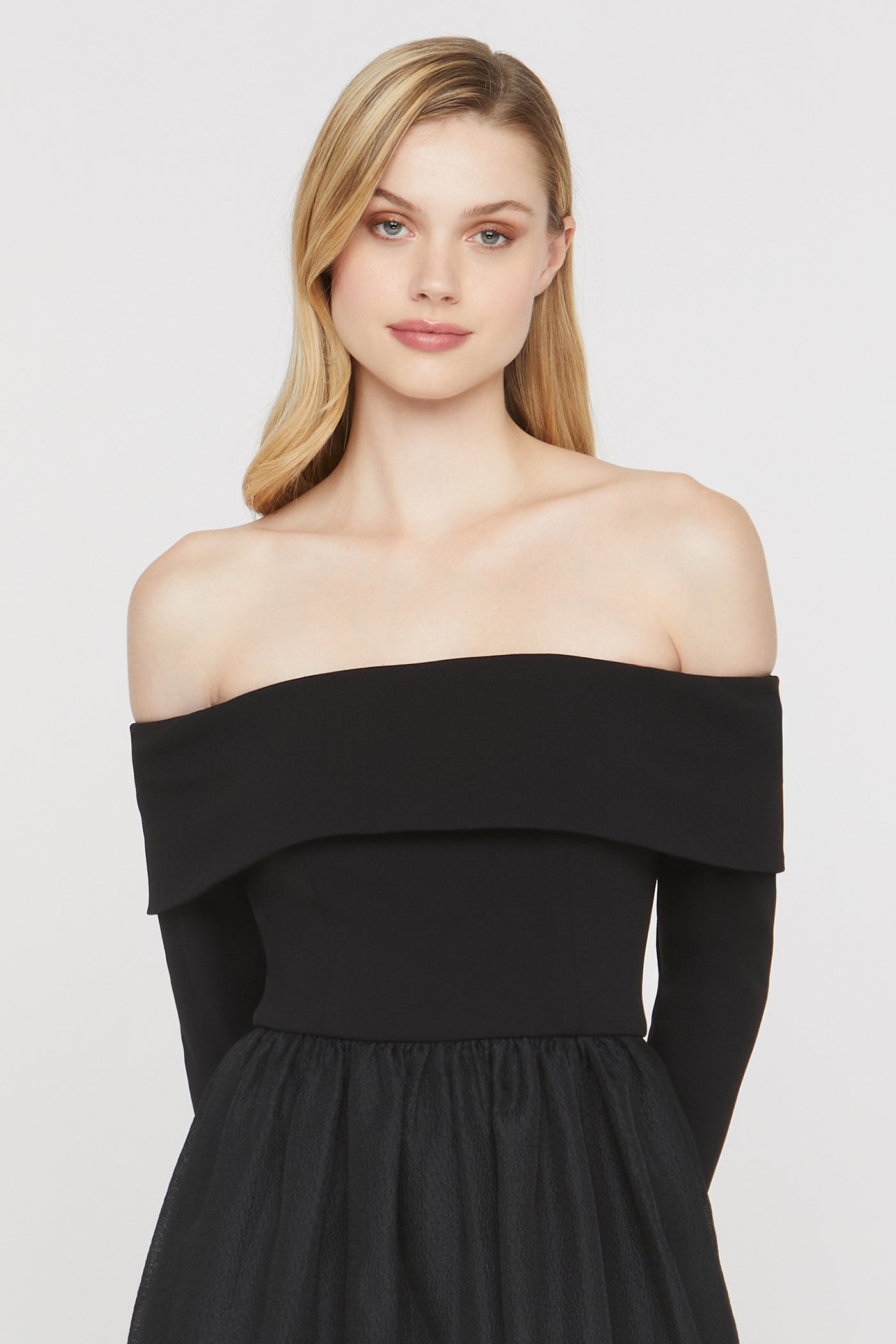 Woman wearing a black off-shoulder dress against a white background
