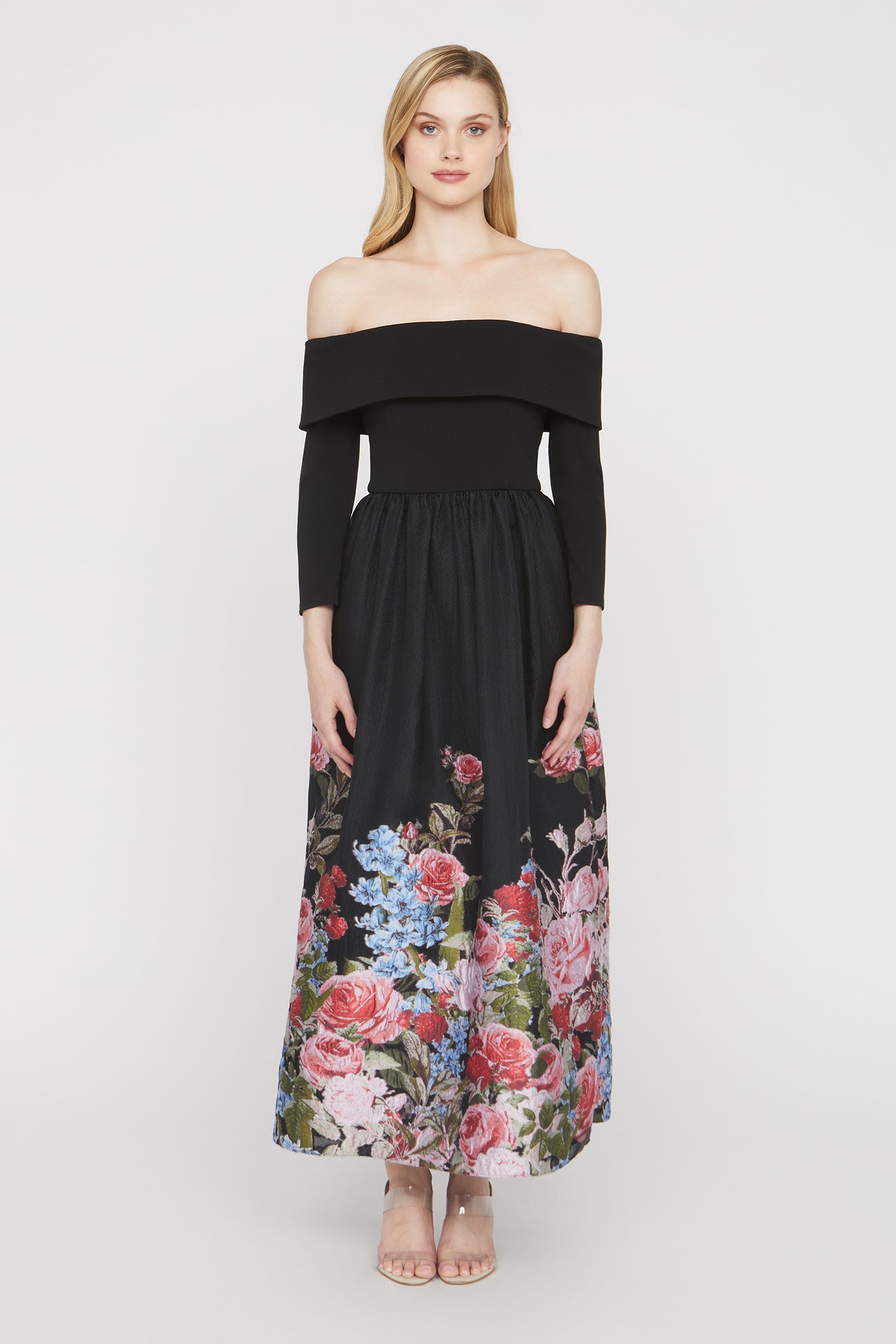Woman wearing a black off-shoulder dress with a floral skirt on a white background