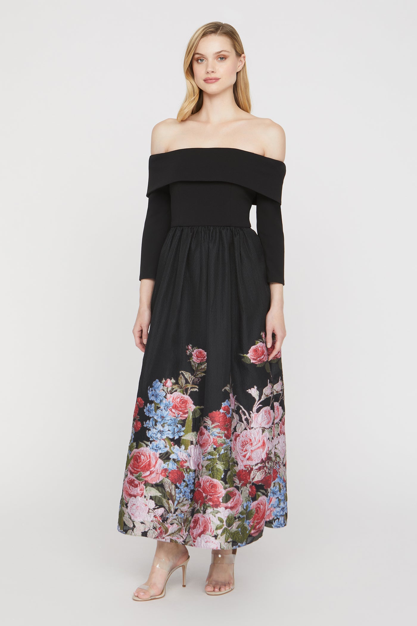 Woman wearing a black off-shoulder dress with floral pattern on a white background