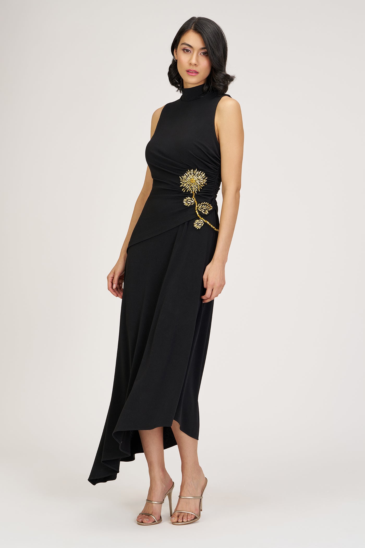 Woman wearing a black dress with gold embellishments on a white background