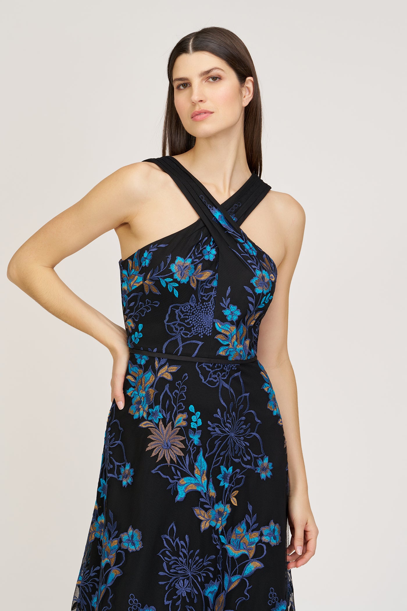 Woman wearing a black floral dress with blue and purple patterns on a beige background