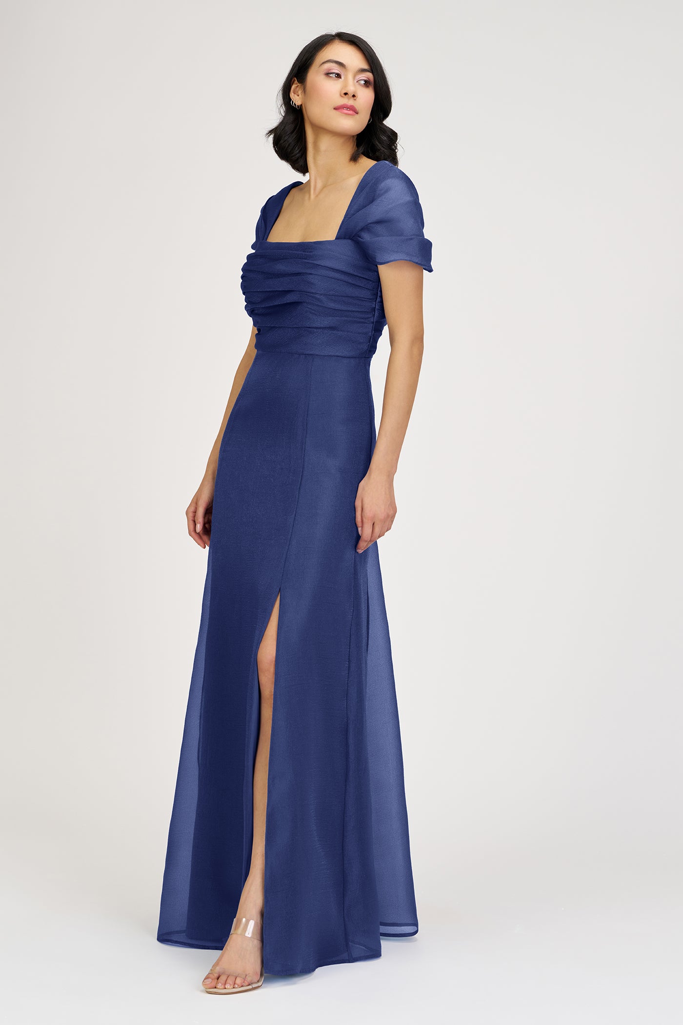 Woman wearing a blue evening gown with a slit on a white background
