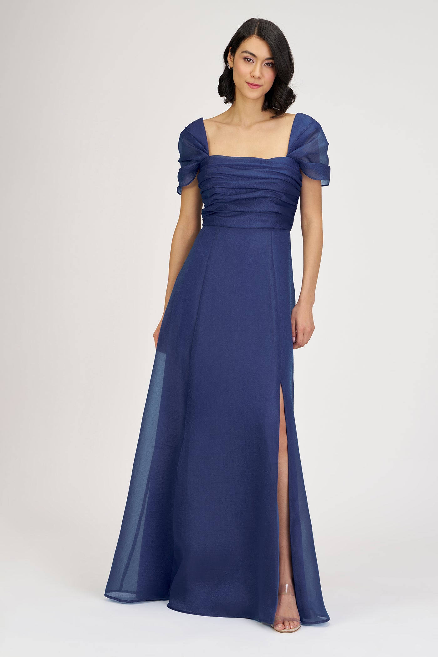 Woman wearing a blue evening gown with a slit on a white background