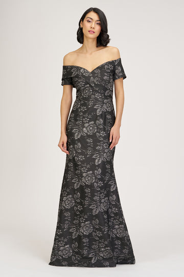Woman wearing a black floral off-shoulder gown on a white background