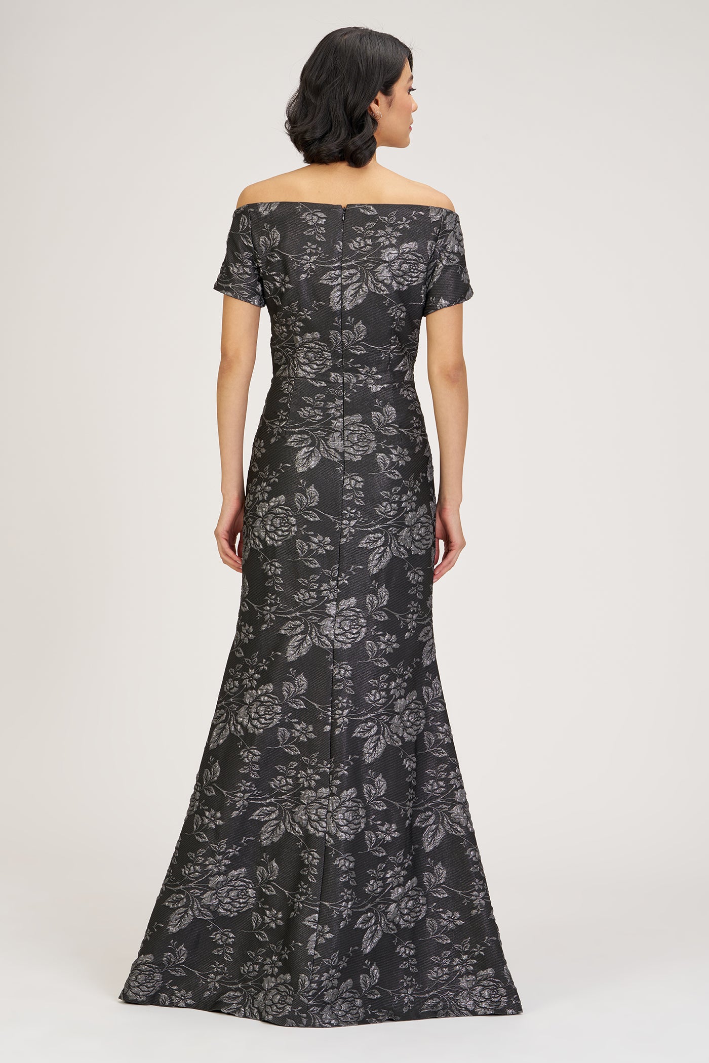Woman wearing a black floral off-shoulder gown on a white background