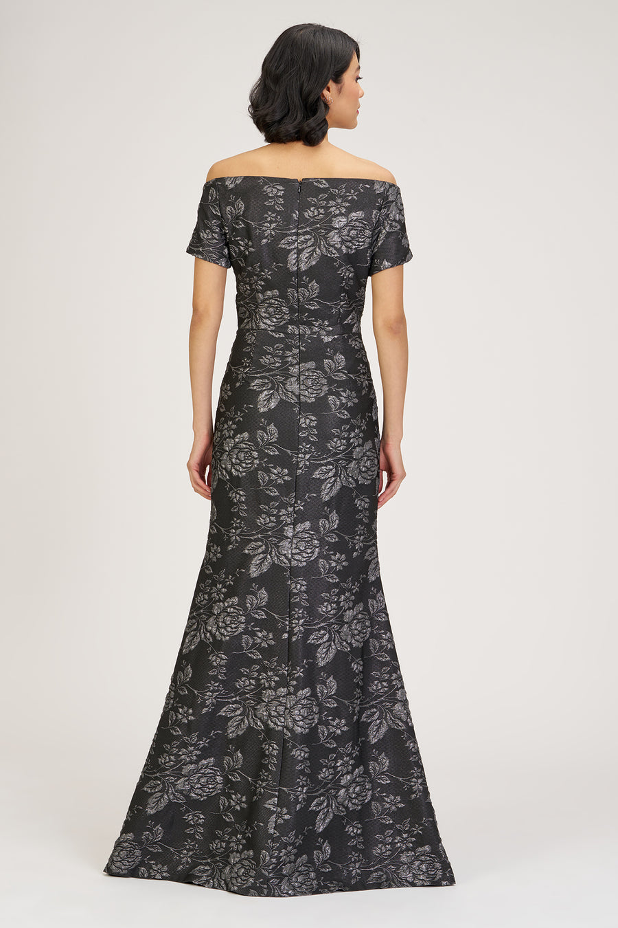 Woman wearing a black floral off-shoulder gown on a white background
