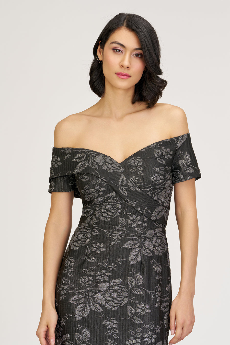 Woman wearing a black off-shoulder dress with floral pattern on a white background
